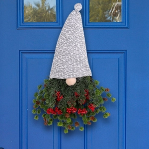 Couronne de gnome de Noël avec baies rouges et chapeau gris sur une porte en bois bleu
