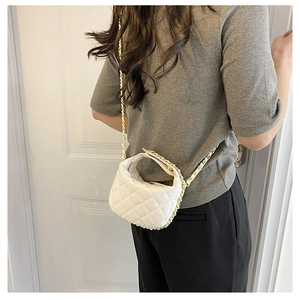 Detailed view of white quilted mini bag with woven gold chain strap worn cross-body