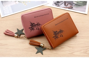 Close-up of mini leather coin purses with fringe tassels and star pendants on wood background