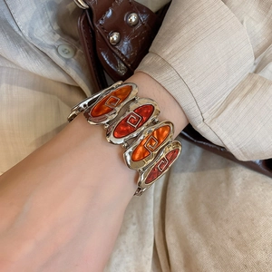Macro shot of vintage silver oval bracelet with orange enamel and spiral geometric texture