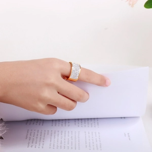 Close-up of a wide 18k gold plated ring with paved white zircons worn on a hand