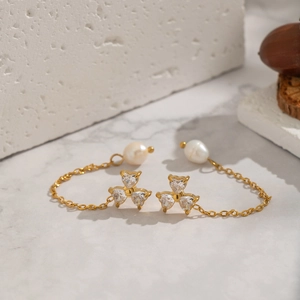 Detail of gold chain earrings with zircon heart accents and white freshwater pearls