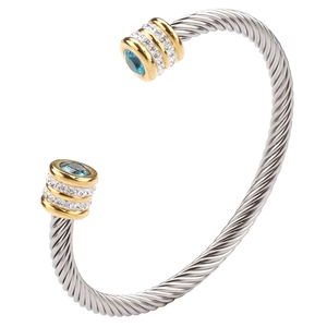 Close-up of cable cuff bracelet with blue gemstones and sparkling crystals in silver gold tone