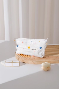 Close-up of a white textured polka dot makeup bag with colorful spots and brand tag