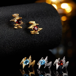 Macro shot of gold and silver stud earrings with oval red and blue gemstones and reflections