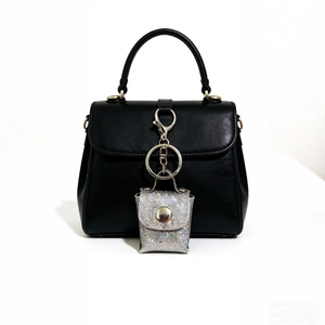 Close-up of a silver glitter mini storage pouch charm on a black leather handbag