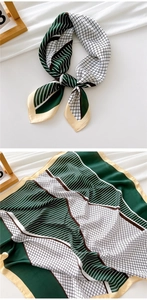 Detail showing the dark green geometric pattern and silk-like texture of the square scarf