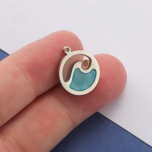 Detailed close-up of a silver stainless steel circular pendant with a blue wave pattern