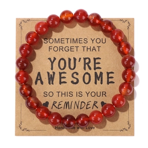 Close-up of red agate beaded bracelet on a kraft card with inspirational message