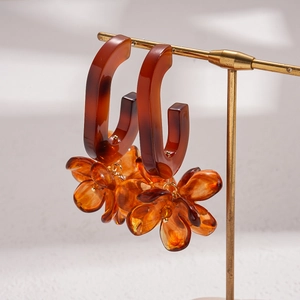 Vintage amber resin floral drop earrings with gold accents on a jewelry display stand