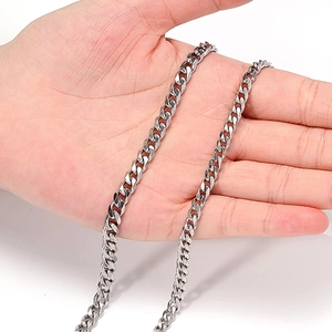 Polished silver stainless steel Cuban link chain necklace held by hand for scale