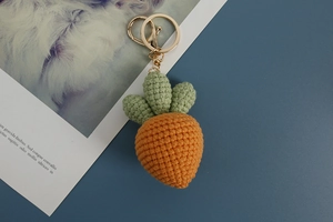 Macro shot of handmade crochet carrot keychain with green leaves and metal clasp details