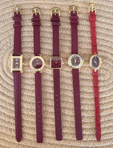 Collection of women's watches with burgundy leather straps and golden cases on fabric