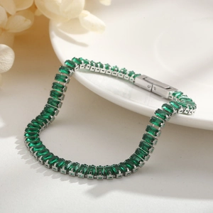 Elegant silver tennis bracelet with emerald-cut green zircons on white ceramic plate