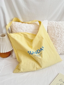 Detail shot of a yellow canvas tote bag with blue summer typography on white fabric