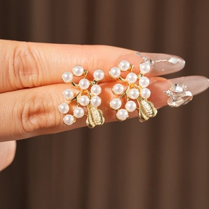 Detailed view of vintage gold floral branch earrings with white pearls on a model