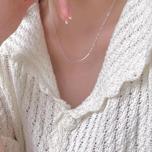 Close-up of minimalist S925 sterling silver curved bar smile necklace worn by model