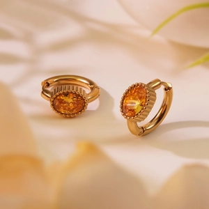 Détails macro de boucles d'oreilles dorées avec zircon jaune et sertissage perlé