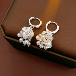 Close-up of silver bell earrings with white and pink pearls on a jewelry box edge