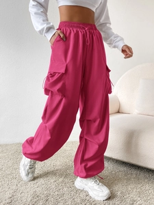 Detail of pink cargo pants featuring elastic drawstring waist and side flap pockets