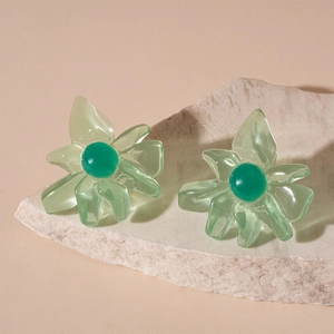 Detailed macro view of translucent green resin flower earrings on a white stone base