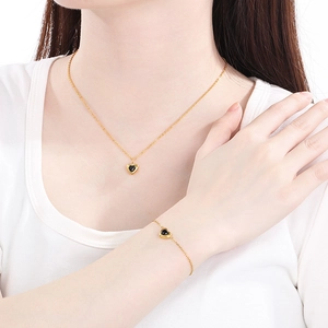 Gros plan d'un mannequin portant un ensemble bijoux en acier 18k avec cœurs noirs