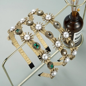Détail du serre-tête baroque doré avec texture tressée, pierres d'émeraude et perles
