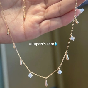 Detail of gold water drop charms and crystals on a fine chain necklace shown on hand