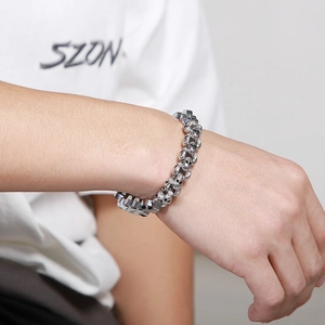 Detailed view of silver gothic skull and thick square chain bracelet on male wrist