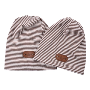 Two striped knit beanies in brown and white with leather patches on white background