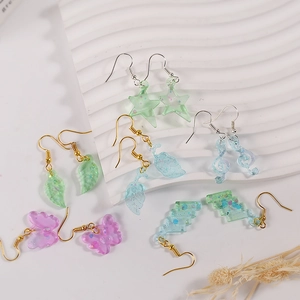 Macro detail of resin earring set with glitter flakes in star and leaf shapes