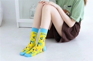 Détail de chaussette en coton jaune avec texte yummy et motifs alimentaires colorés