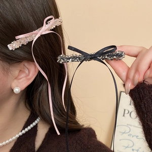 Close-up of pink and black silk bow hair clips with crystal beads on female model