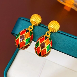 Vintage gold-tone enamel earrings with colorful harlequin pattern on green jewelry box