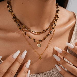 Close-up of layered tiger eye beaded necklace with 18k gold plating and crystal pendant