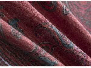 Macro shot of thick paisley pattern fabric in deep red with detailed woven texture
