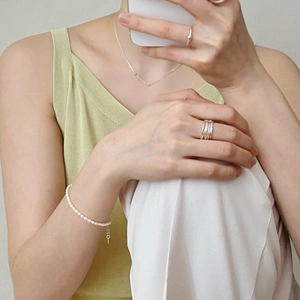 Chic layered look featuring a pearl bracelet and silver rings on a model