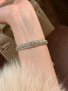 Close-up of vintage hollow lace patterns and zircon micro-pave setting on silver bangle