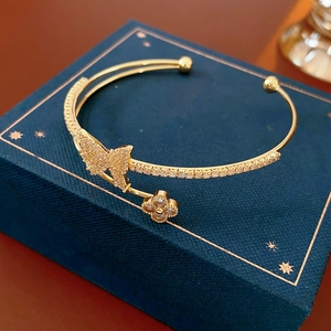 Close-up of golden butterfly and clover bangle with zircon pavé on a jewelry box