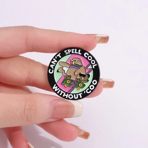 Enamel pigeon on skateboard badge with 'Can't spell cool without coo' text