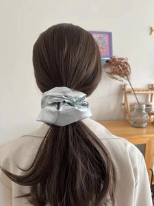 Silver metallic oversized scrunchie shown in use on a low ponytail hair styling