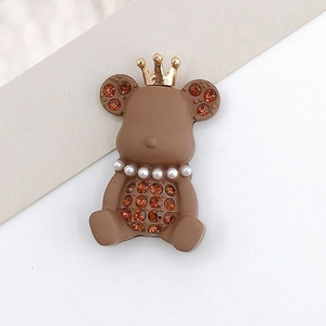 Detailed view of a brown resin bear charm with golden crown and pearl necklace decor
