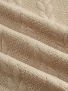 Macro shot showing beige jacquard embossed fabric texture of men's premium hoodie