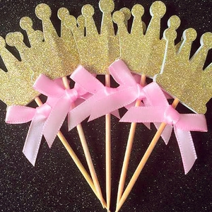 Golden glitter crown cake toppers with pink ribbon bows for baby birthday decorations