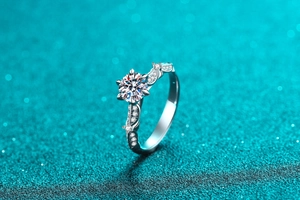 Macro shot of silver moissanite ring with circular main stone and curved pavé diamond band