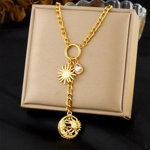 Dettaglio della collana dorata con ciondoli a forma di sole, luna e cristallo lucido