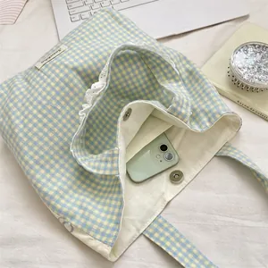 Macro shot of blue gingham canvas tote bag with white lace trim and magnetic closure