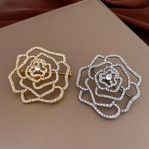 Détail d'une broche rose ajourée avec strass blancs étincelants en plaqué or et argent