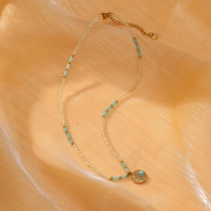 Detail of beaded necklace with sunflower pendant and blue crystal on silk fabric