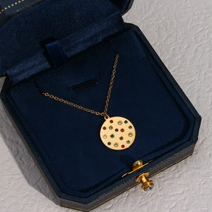 Golden round necklace with colorful crystal zircons inside a blue velvet jewelry box